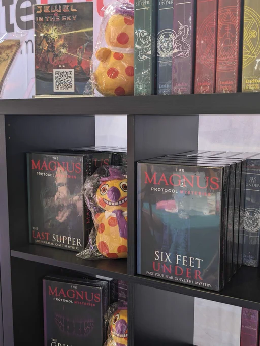 A photograph of The Magnus Protocol Mysteries Game on shelves, with a plush "Mr Bonzo" toy. 