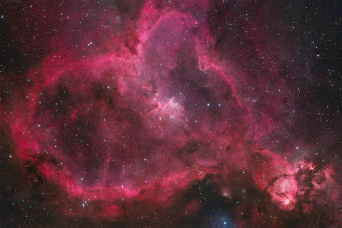A young, hot open cluster drives the nebula's vivid glow at its core — Melotte 15 — which contains several massive O-type stars radiating intense ultraviolet radiation. This radiation ionizes the surrounding hydrogen gas, producing the characteristic deep-red Hα emission that makes IC 1805 so photogenic.