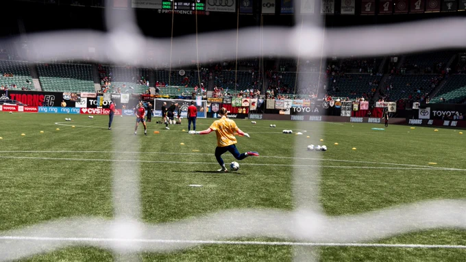 Mandy kicking a ball during warmups at PORvUTA with the goal net framing her