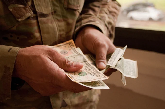 U.S. Army Soldier holds money. (U.S. Army photo by Kristen Wong)