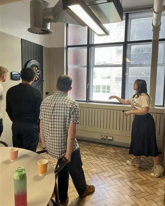 Attendees playing darts and chatting in a breakout area during a keep warm event.