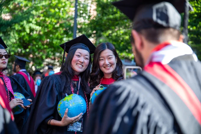 Two graduates posing as another graduate takes their photo.