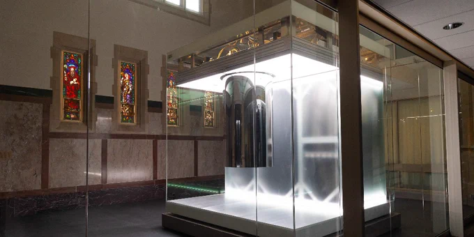 A modern space featuring a sleek, transparent enclosure displaying an IBM Quantum System One. The setting includes stained glass windows in the background, adding a historical contrast to the high-tech equipment.