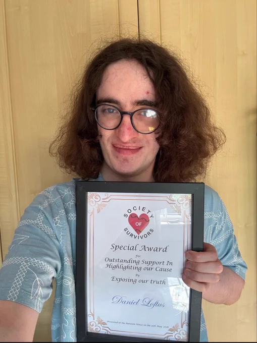 Photo of me holding a framed award which reads: “Special Award to Outstanding Support in Highlighting our Cause by Exposing our Truth” with my name underneath.