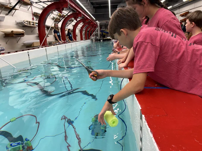 AACPS students at USNA hydro lab navigate underwater ROVs.