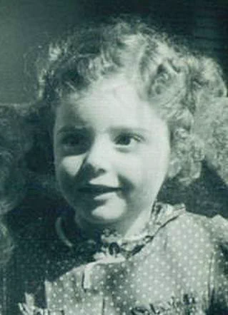 Vintage black-and-white portrait of a young girl with curly hair, wearing a polka dot dress and smiling at the camera.
