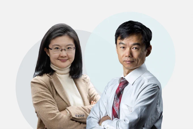 PhD candidate Lily Haopu Ren and PhD student Yong Zhao stand side by side with arms crossed. Lily, an Asian woman, wears glasses, a beige blazer, and a cream turtleneck; Yong, an Asian man, wears a light blue dress shirt and red tie.