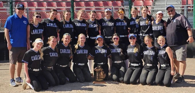 girls varsity softball team posing for a picture with their coaches and the trophy