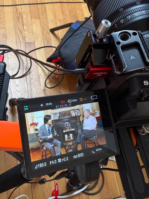 Camera screen showing behind-the-scenes footage of Robert Zoellick episode