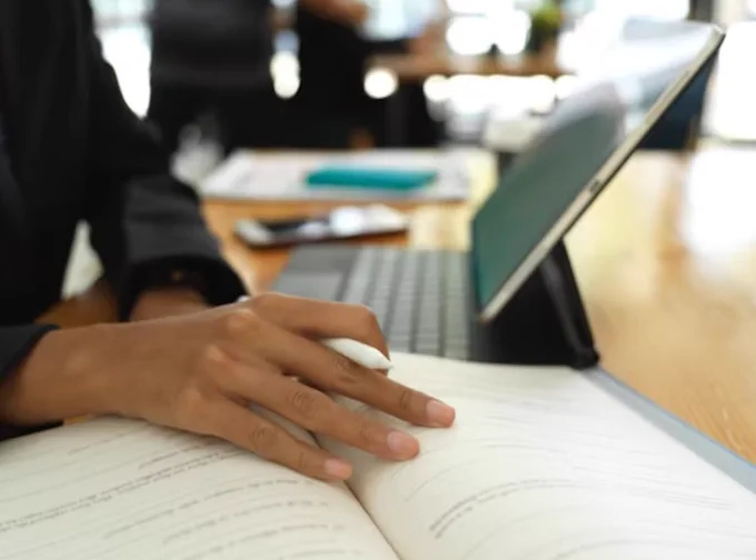 book and laptop open on desk. 