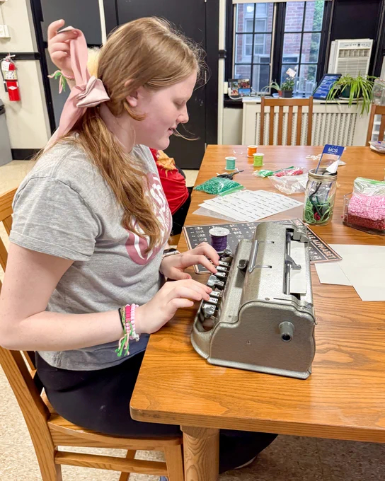 A girl does braille art on a Perkins Brailler