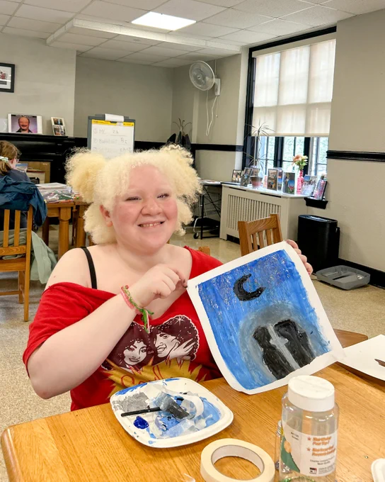 A girl shows off her oil pastel painting