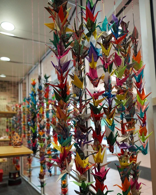 Colorful origami cranes hanging on vertical strings inside a display case at the Edmond Library.