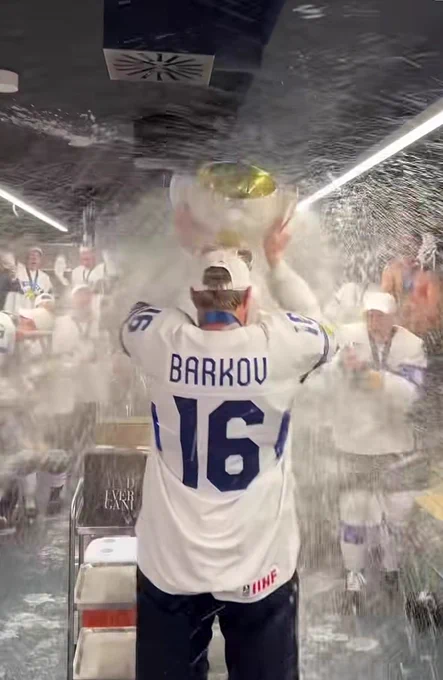 barkov lifting the cup in the finland locker room at worlds while being sprayed with champagne