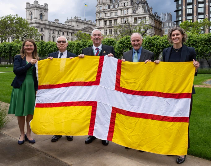 Speaker posing for a photo with Dorset flag and a group of MPs from Dorset.