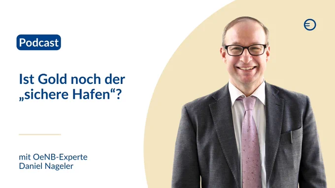 Ein Mann mit Brille in grauem Anzug und rosa Krawatte lächelt vor einem hellen Hintergrund.