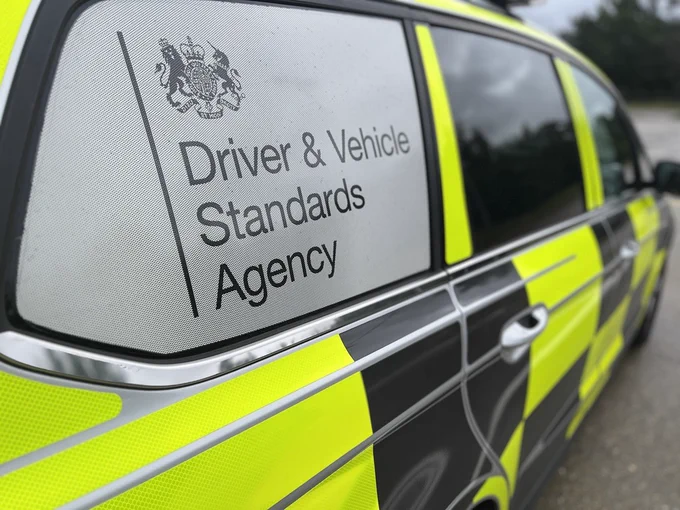 Close-up of a Driver & Vehicle Standards Agency marked vehicle with reflective yellow and black checkered pattern on the side.