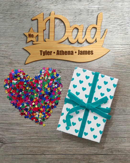 Custom Bamboo Sign With Number One Dad Cutout And Engraved With 3 Kids Names On Table With Gift And Colorful Confetti