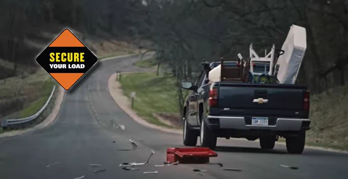 Image of a truck traveling down a road with tools and other items falling out of the truck bed.