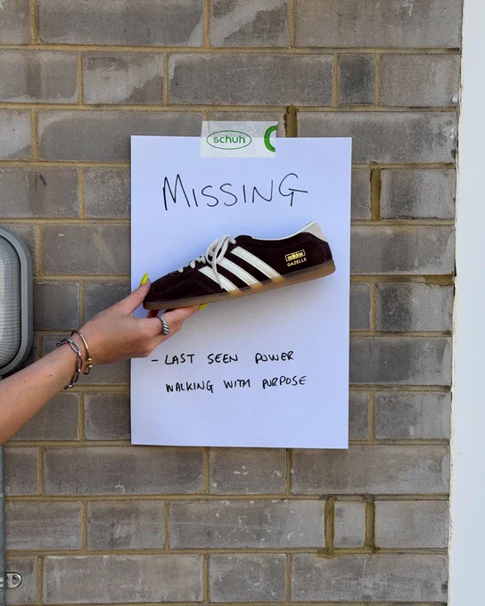 An image of a person's hand holding a black adidas Gazelle Lo Pro trainer in front of a white piece of paper with text saying "Missing - last seen power walking with purpose".
