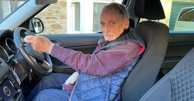 A photo of Tony behind the wheel of his car.