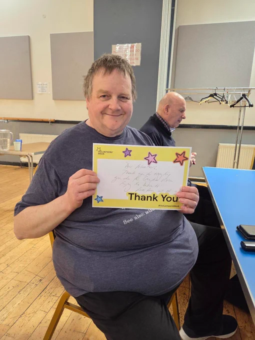We see a photo of Dr Paul Harper, a much-admired Croydon Vision Volunteer. He is holding a "Thank You" note prepared by Croydon Vision Staff. Although Paul is very tired after a busy weekend helping one of our Members with his house move, Paul continues to smile and has been supporting us today as always. A real super star! 