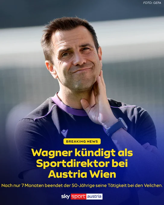 Ein Mann mit kurzen braunen Haaren und einem strahlenden Lächeln wird in einer Sportjacke gezeigt.