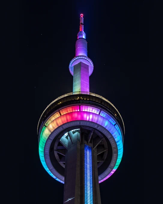 Closeup of the CN Tower at night lit in rainbow colours / Gros plan de la Tour CN illuminée en arc-en-ciel la nuit  