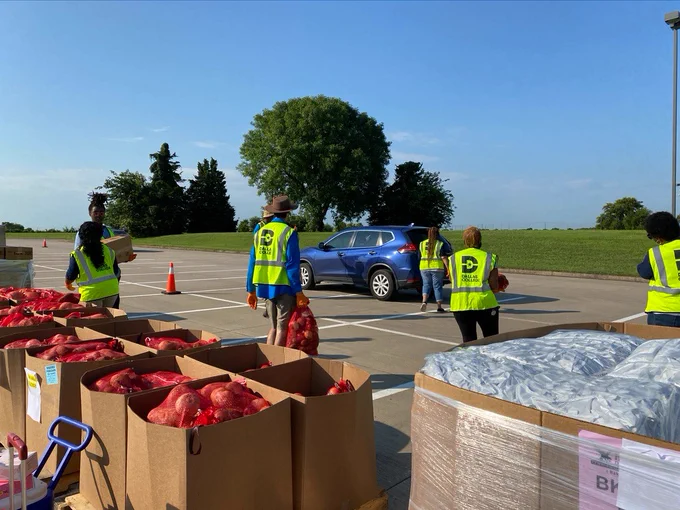Volunteers help load food into a car.