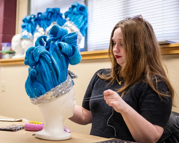 Boise State costume design student sewing a wig for the student theatre production of Grease. 
