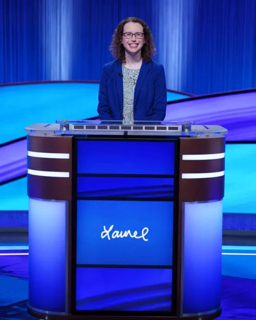 Laurel Gilmer standing behind a Jeopardy! game show desk