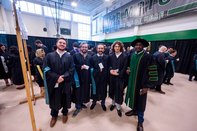 A group of graduates in caps and gowns walk in a procession during a graduation ceremony