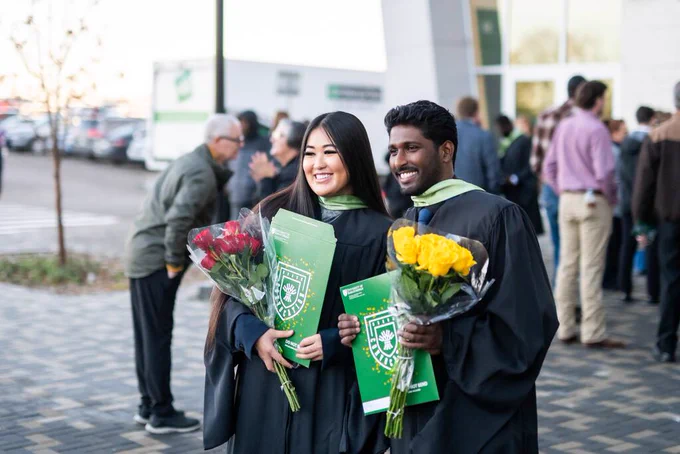 A group of graduates in caps and gowns walk in a procession during a graduation ceremony