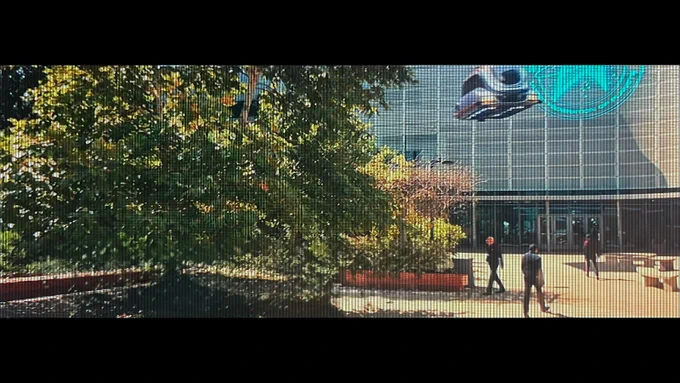 Five officers walking, a small spacecraft prepares to land, and two people walking in front of the University Center in the future (2385). 