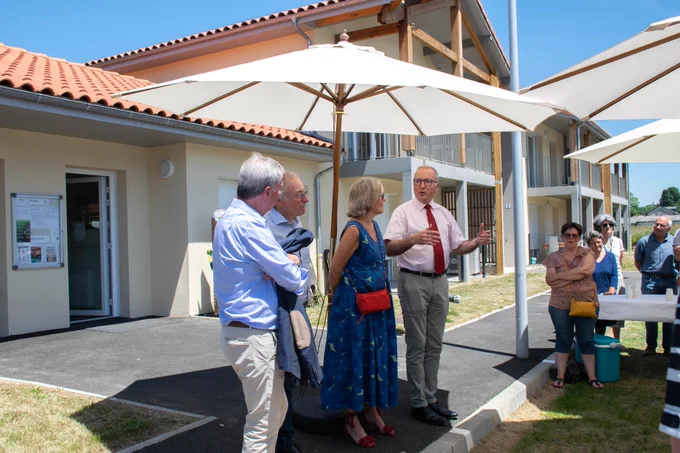 Le préfet des Hautes-Pyrénées s’exprimant face à un petit groupe de personnes. Ils sont réunis en extérieur sous un grand parasol blanc, devant la résidence Soleil des Cimes.