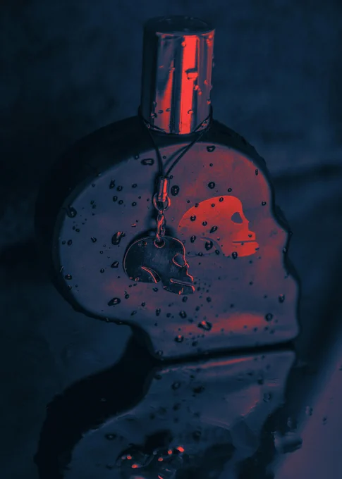 Dark and moody close-up of a skull-shaped perfume bottle with water droplets on a reflective surface.