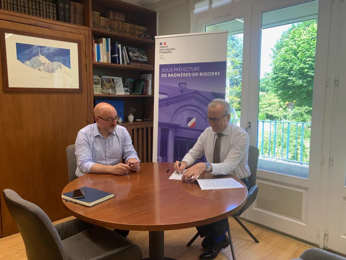 M. le préfet des Hautes-Pyrénées et le président de la communauté de communes Neste Barousse autour d'une table ronde en bois dans un bureau officiel pour la signature de la convention.