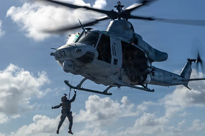 Marine fast ropes from a helicopter onto a ship flight deck during maritime insertion training.