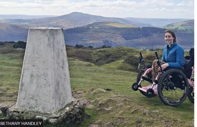 Bradley Handley in her all terrain wheelchair next to a countryside monument