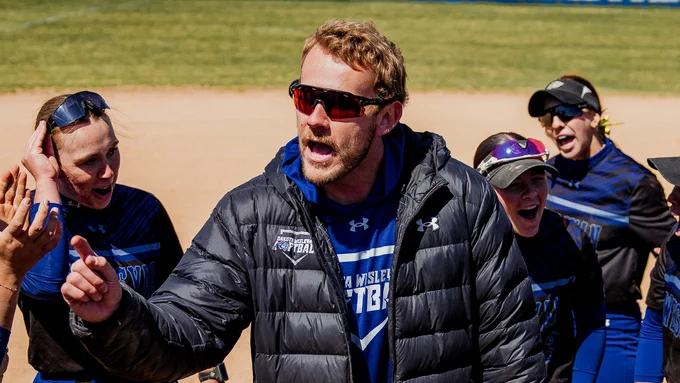 Stephen Oswald Jr. in the middle of the DWU Softball team huddle following a game, photo by ThirDWheel Photo