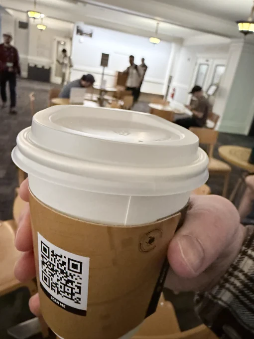 A paper coffee cup with the back of the lid aligned with the seam.