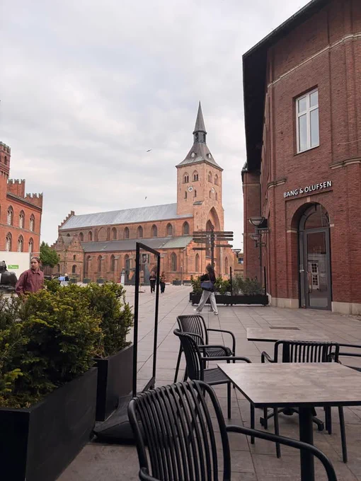 A cafe with outdoor tables and chairs situated in front of a church, creating a cozy atmosphere for patrons.