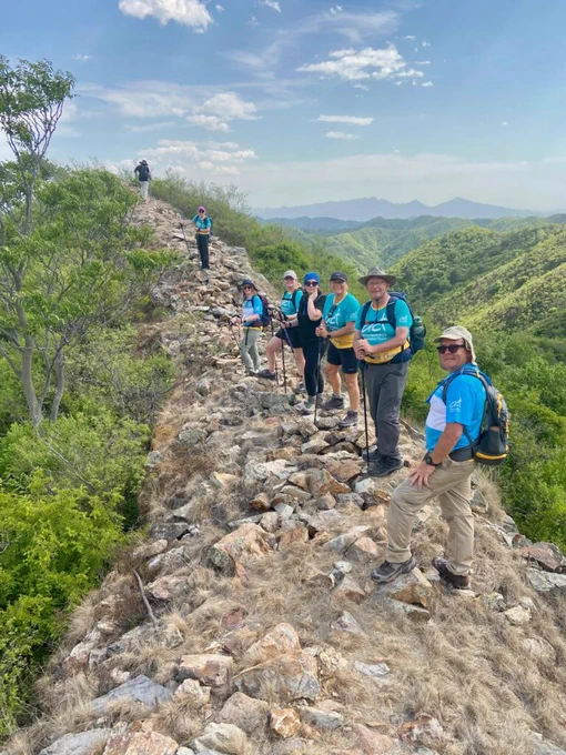A group of people trekking up a mountain overlooking a green forest
