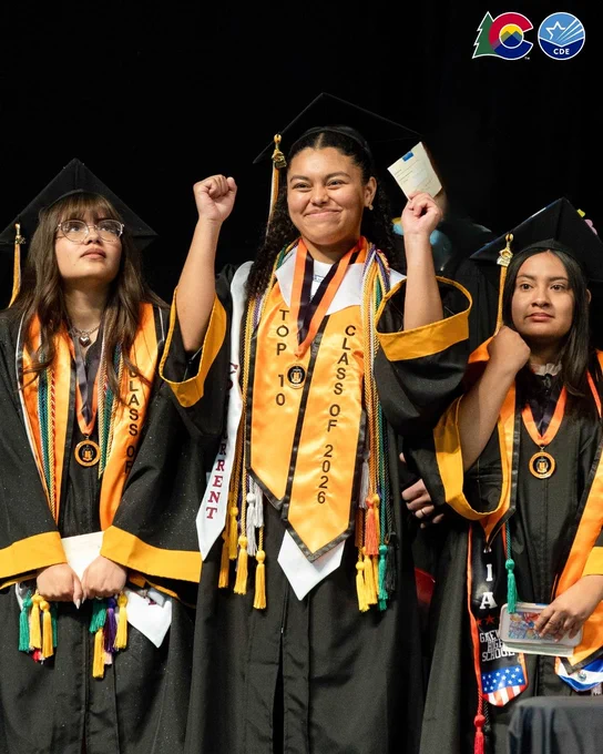 Graduates in caps and gowns celebrate on stage, wearing sashes that read "Top 10 Class of 2026." The image includes logos for Colorado Education Initiative.