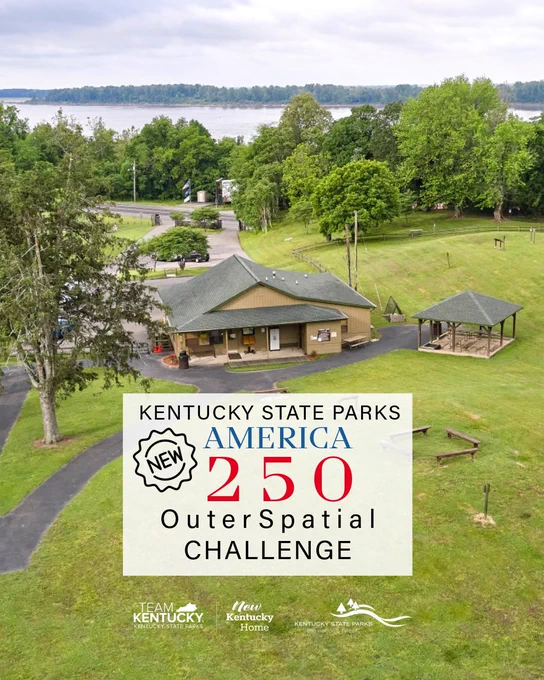 A scenic view of Kentucky State Parks featuring a grassy area with a building and a gazebo. A lake is visible in the background. A poster in the foreground reads "Kentucky State Parks, America 250 OuterSpatial Challenge." Logos for Team Kentucky and Kentucky State Parks are at the bottom.