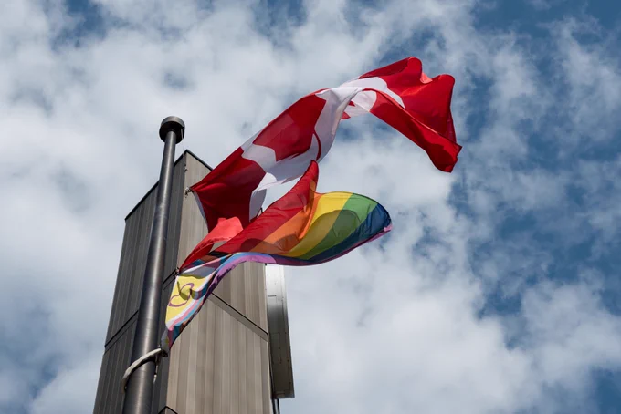 Canadian flag and the Progress Pride flag flying on a flagpole beside the TDSB's Head Office.