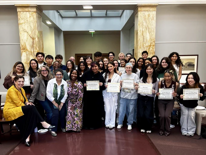 A group photo of students, faculty, and staff. Students hold certificates of completion.