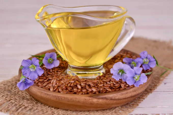Flax seed oil in a glass bowl. Surrounded by flax seeds.