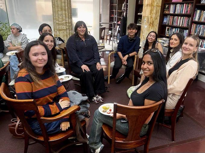 A group of students seated in a circle indoors, smiling at the camera. 