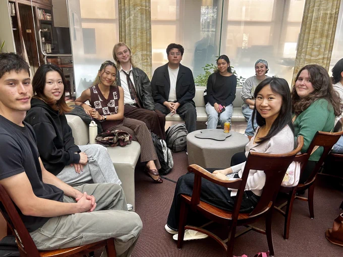 A group of nine students sitting in a circle, smiling at the camera.